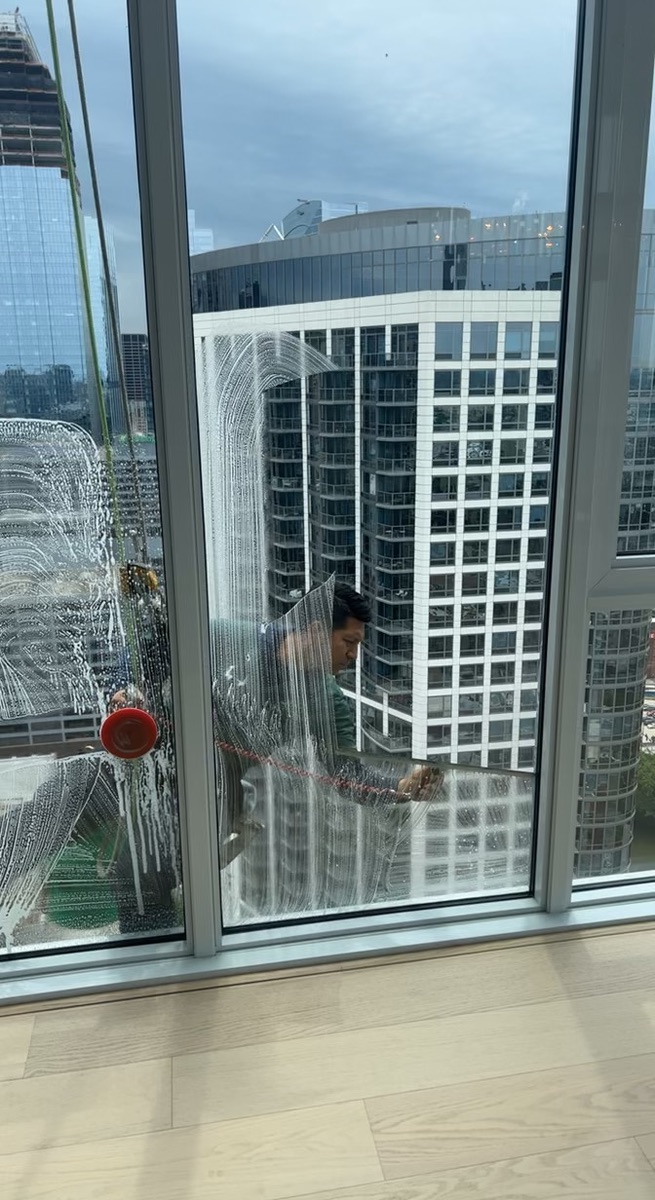 Window cleaner using a squeegee to clean high rise exterior windows in Chicago