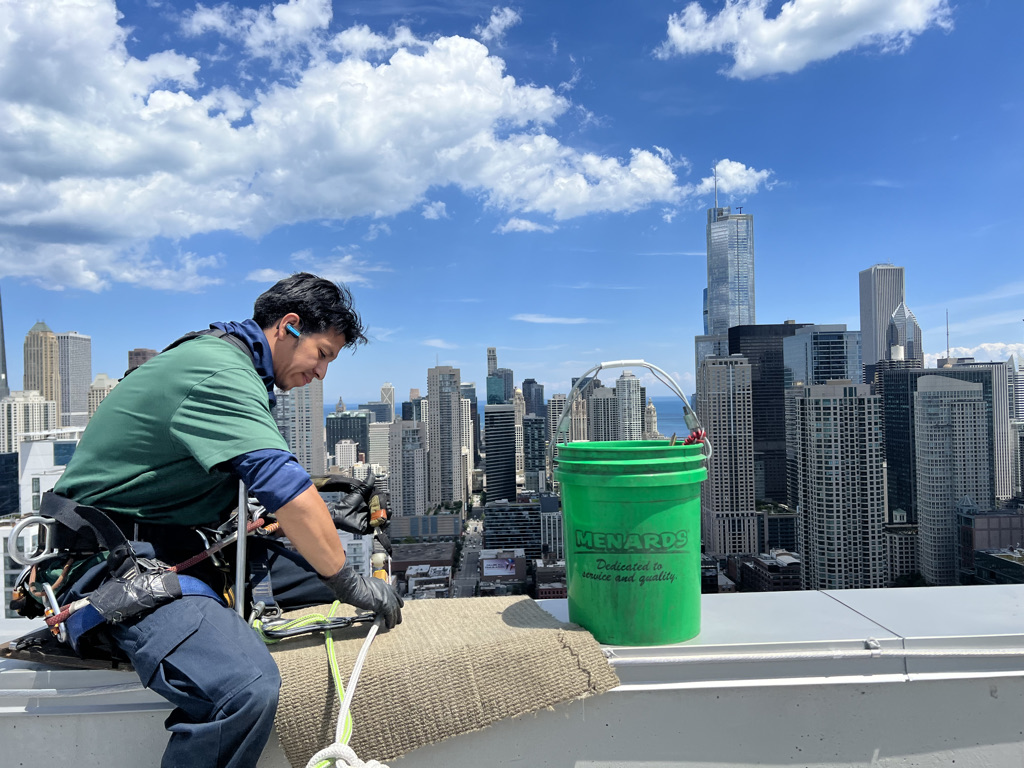 A window washer checks their safety gear ontop of a Chicago skyscraper.