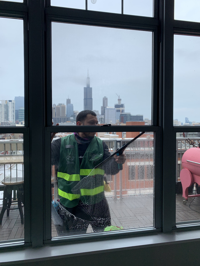 Window washer cleaning apartment building windows with squegee