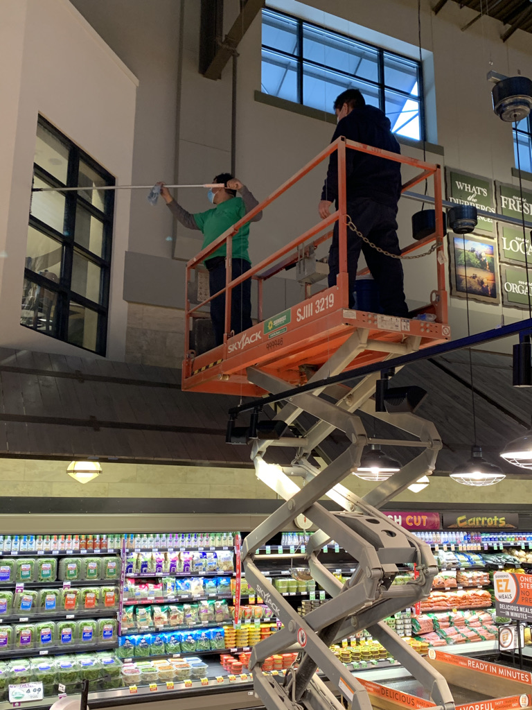 Expert window cleaners team on a lift washing in-store windows